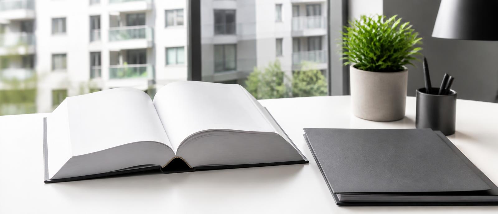 Gesetzbuch und Aktenordner auf einem Schreibtisch vor einem Wohngebäude